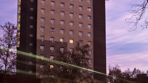 Un grand immeuble d’hôtel, surmonté d’une enseigne bien visible indiquant « ibis HOTEL ».