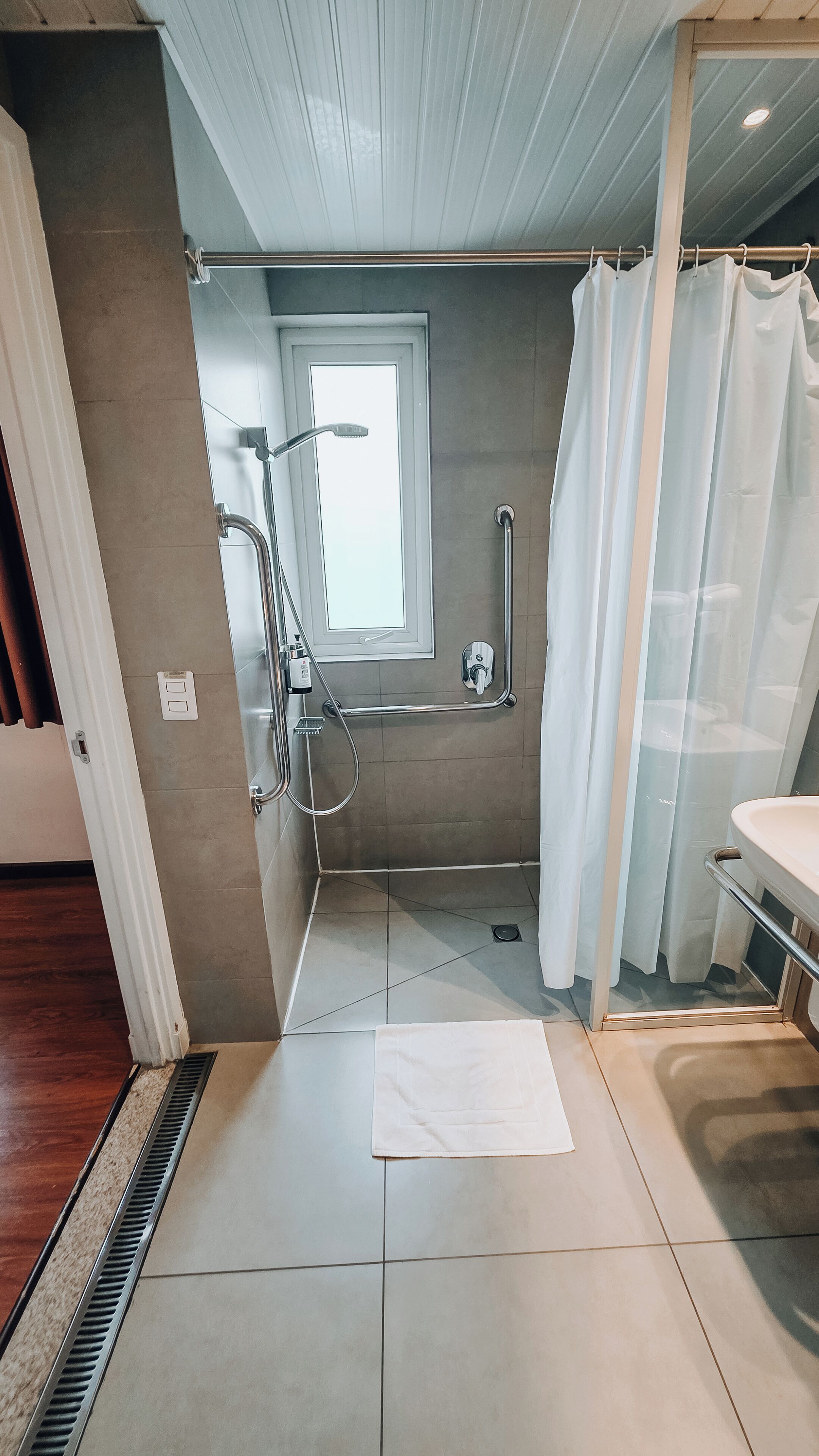 Un baño moderno con cabina de ducha, inodoro con mampara de vidrio y lavamanos blanco.