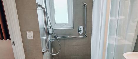 Un baño moderno con cabina de ducha, inodoro con mampara de vidrio y lavamanos blanco.