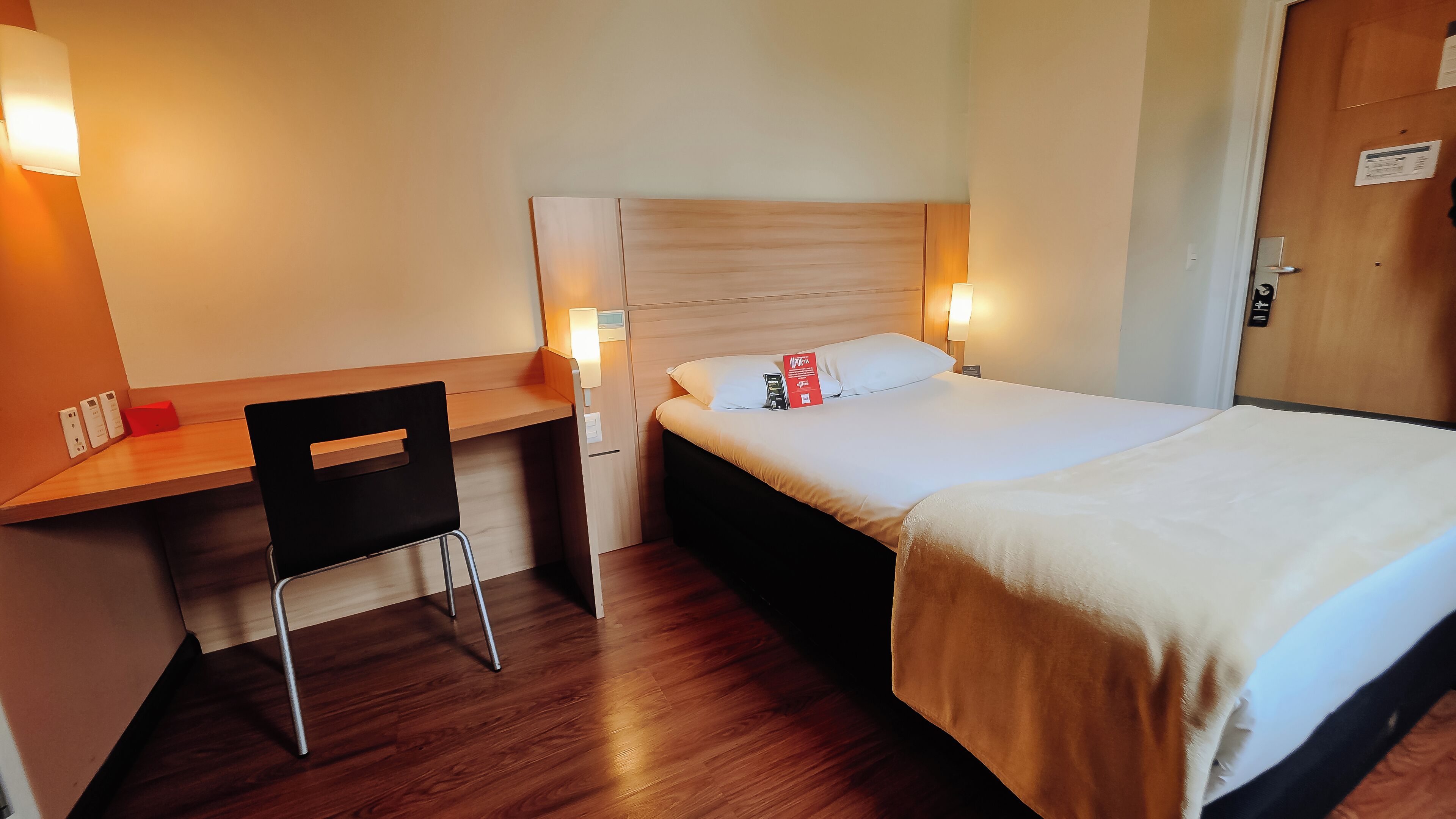 A hotel room with a bed, a desk, a chair, and a nightstand.