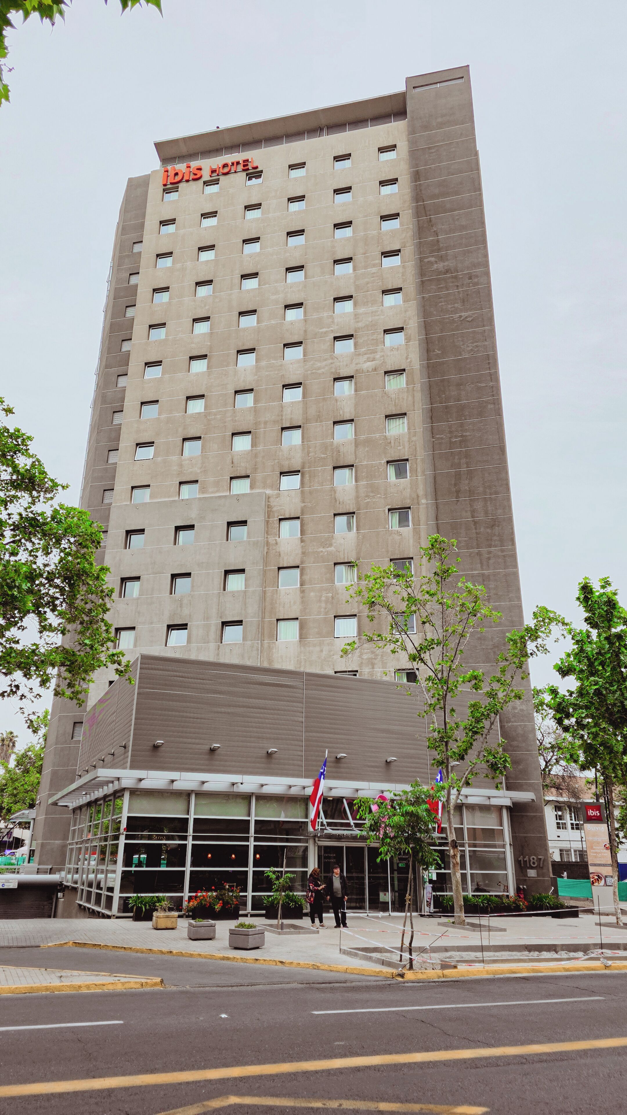 A tall hotel building with a modern facade, multiple windows, and a ground-level entrance with glass doors.