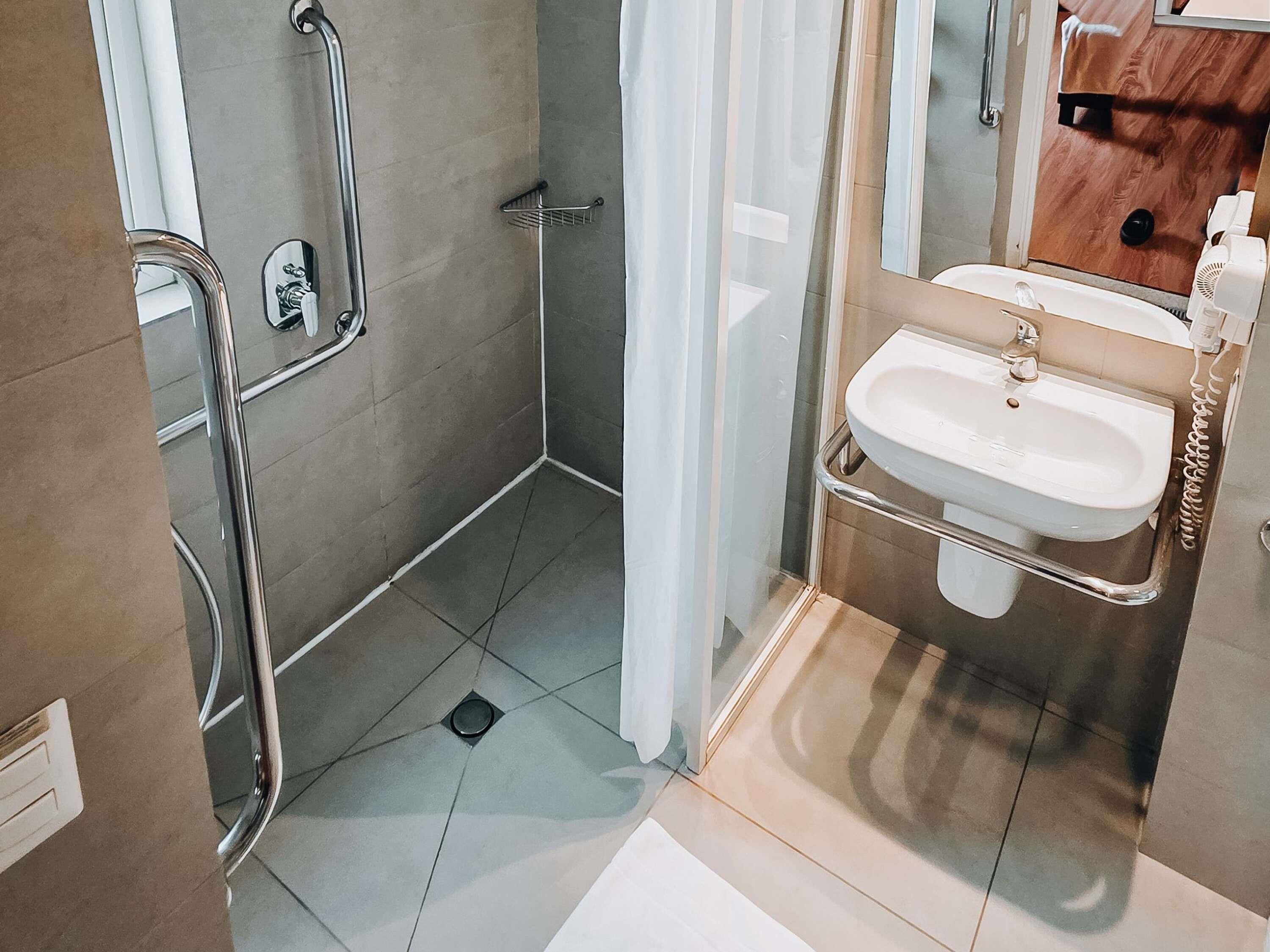 Une salle de bain avec une douche, un lavabo et un miroir.