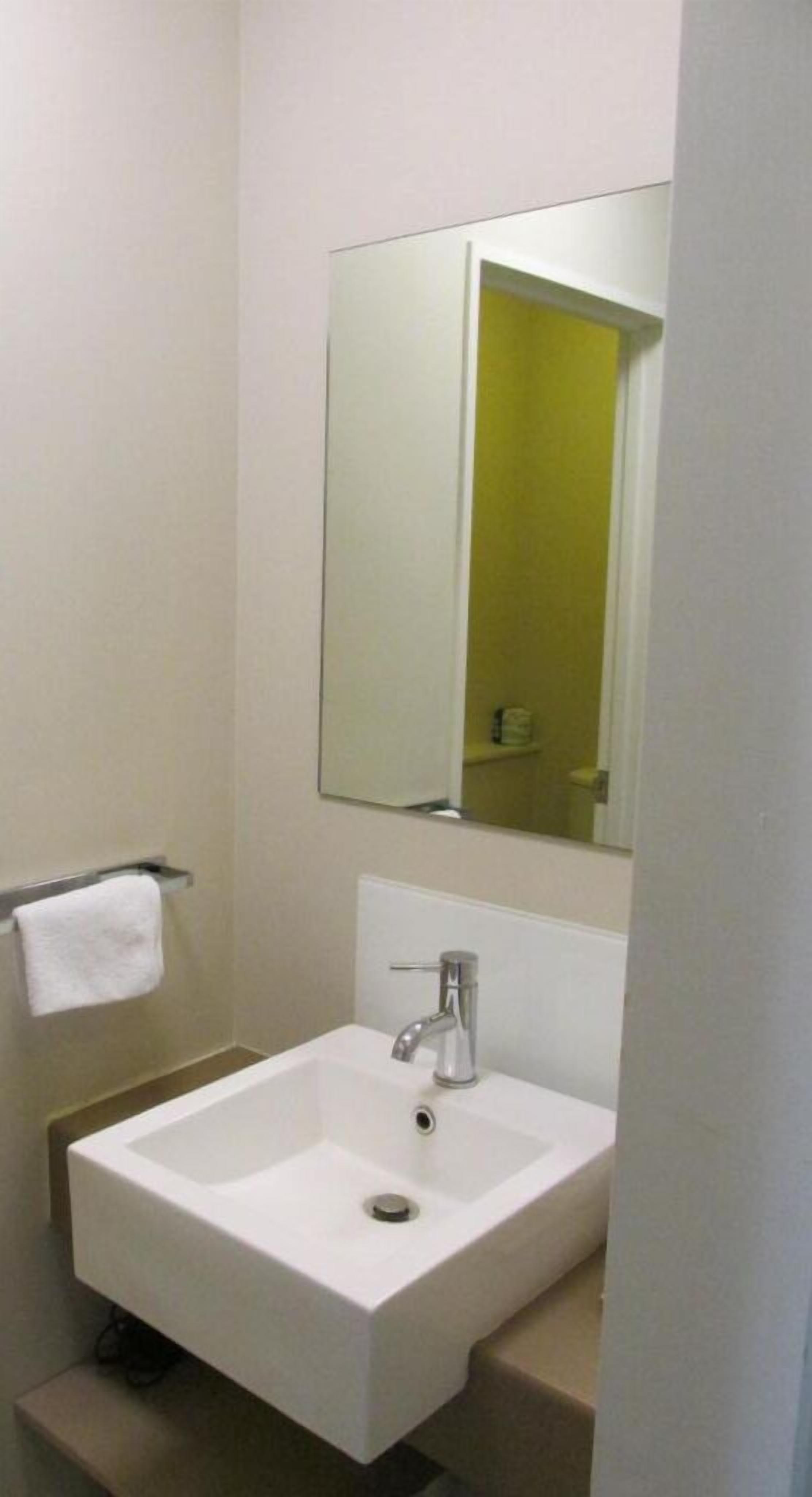 A bathroom with a white sink, a mirror above it, and a towel rack to the left.