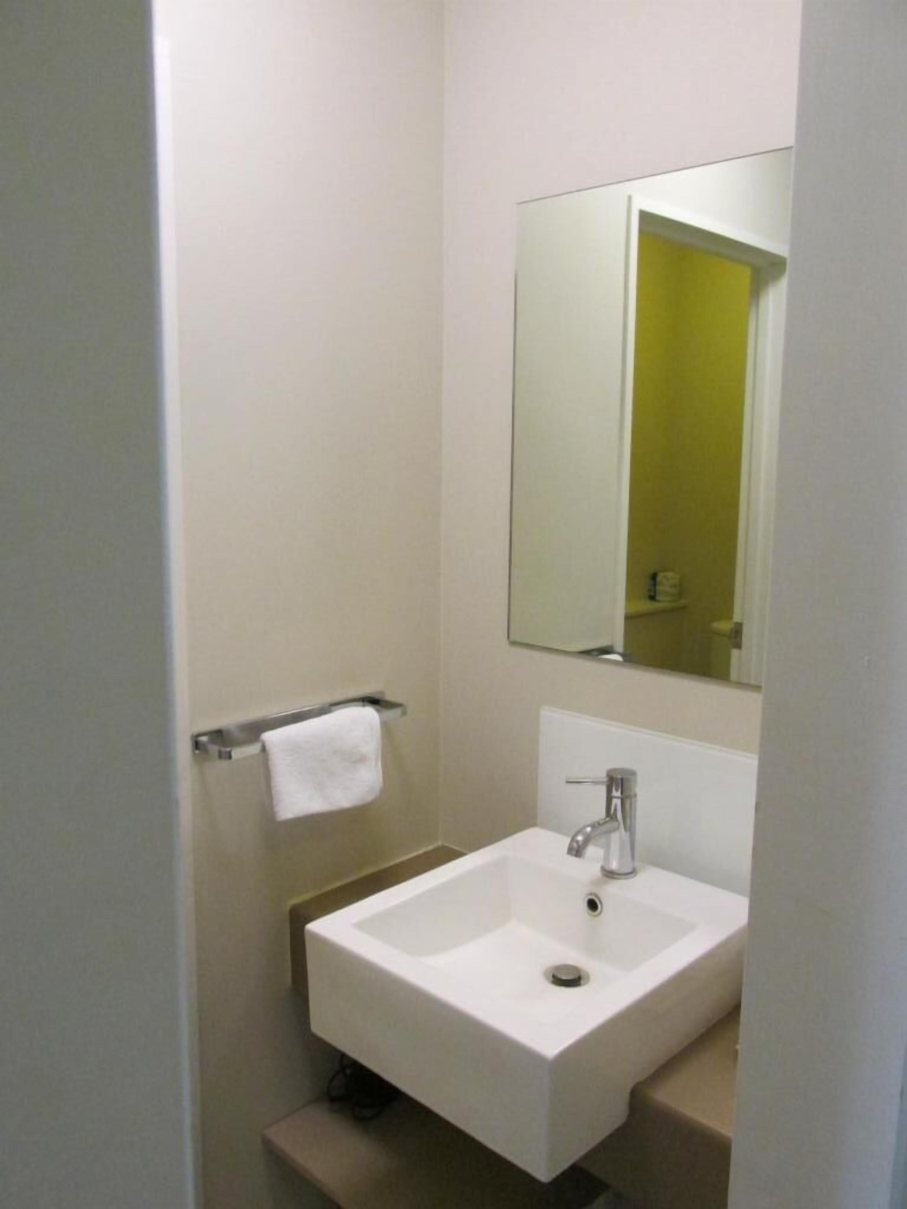 Un baño con un lavamanos blanco, un espejo y un mueble amarillo.