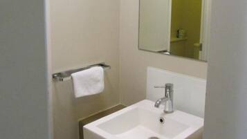 Un baño con un lavamanos blanco, un espejo y un mueble amarillo.