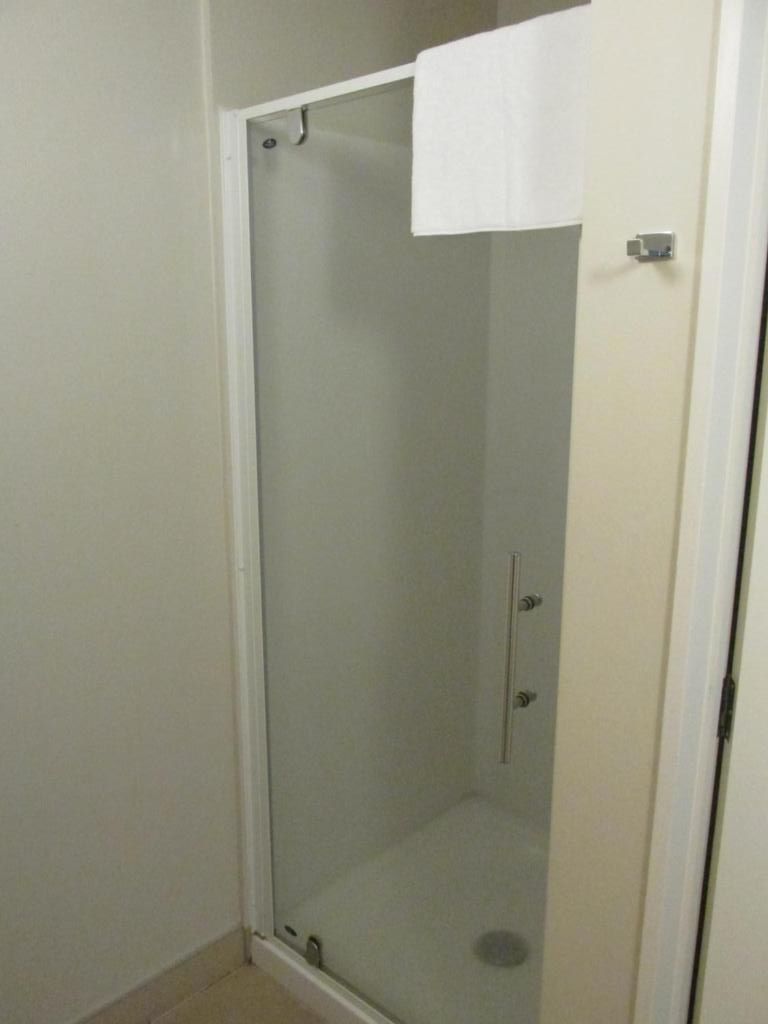 A glass-enclosed shower stall with a white towel hanging on the door.