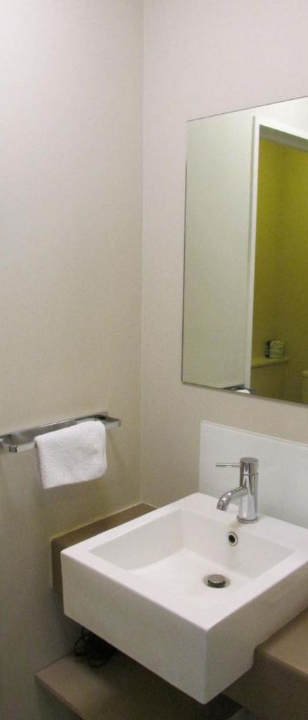 Une salle de bain avec un lavabo blanc, un miroir et un porte-serviettes.