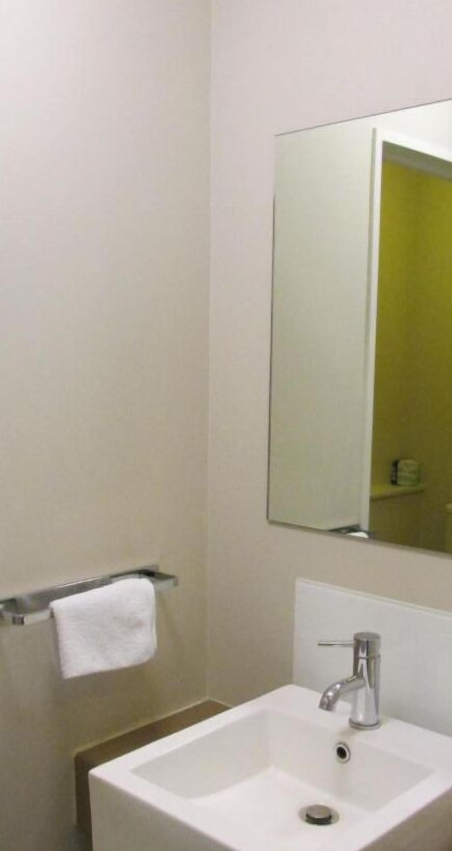 Un baño con un lavabo blanco, un espejo y un perchero para toallas.