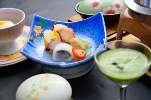 A table with a blue ceramic dish containing sliced fruits and vegetables, a green beverage in a glass, and a teapot. - Kokonoe Yuyutei (Kokonoe)