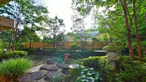Un jardin avec un chemin de pierres, des plantes en pot et une lanterne en pierre traditionnelle.