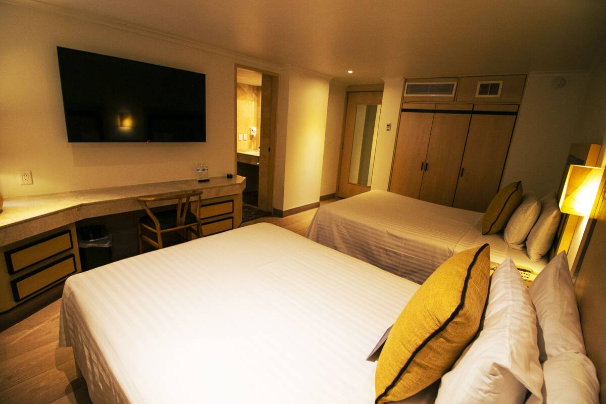 A hotel room with two beds, a desk, a television, and a wardrobe.