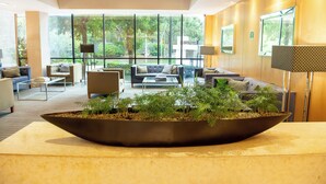 Un vestíbulo moderno con un gran macetero, asientos cómodos y ventanas amplias con vista a zonas verdes.