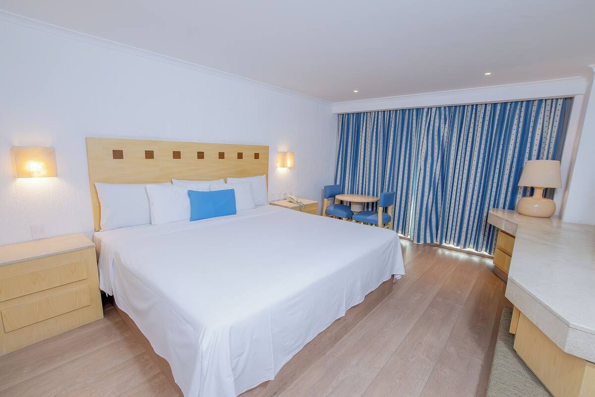 A hotel room with a large bed, bedside tables, a desk, and a chair.