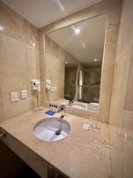 Une salle de bain avec un grand miroir, un lavabo et un espace douche.