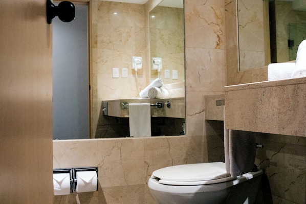 Une salle de bain comprenant des toilettes, un porte-serviettes, un miroir et un espace douche.