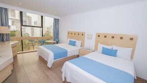Habitación de hotel con dos camas, un escritorio y vistas a la ciudad.