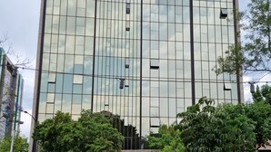 Un edificio moderno con fachada de vidrio y un camión estacionado frente a él.