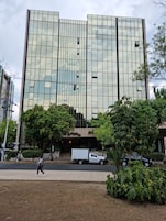 Un edificio moderno con fachada de vidrio y un camión estacionado frente a él.