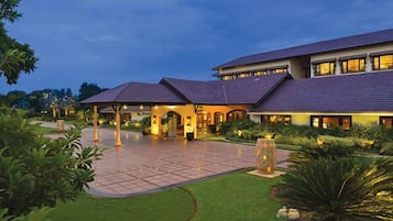 Enter a serene oasis with a spacious entrance area leading to a covered patio surrounded by lush greenery.