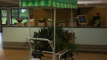 A stationary food cart with a green canopy, a white bicycle, and a sign that reads "Fresh Vegetable Juice".