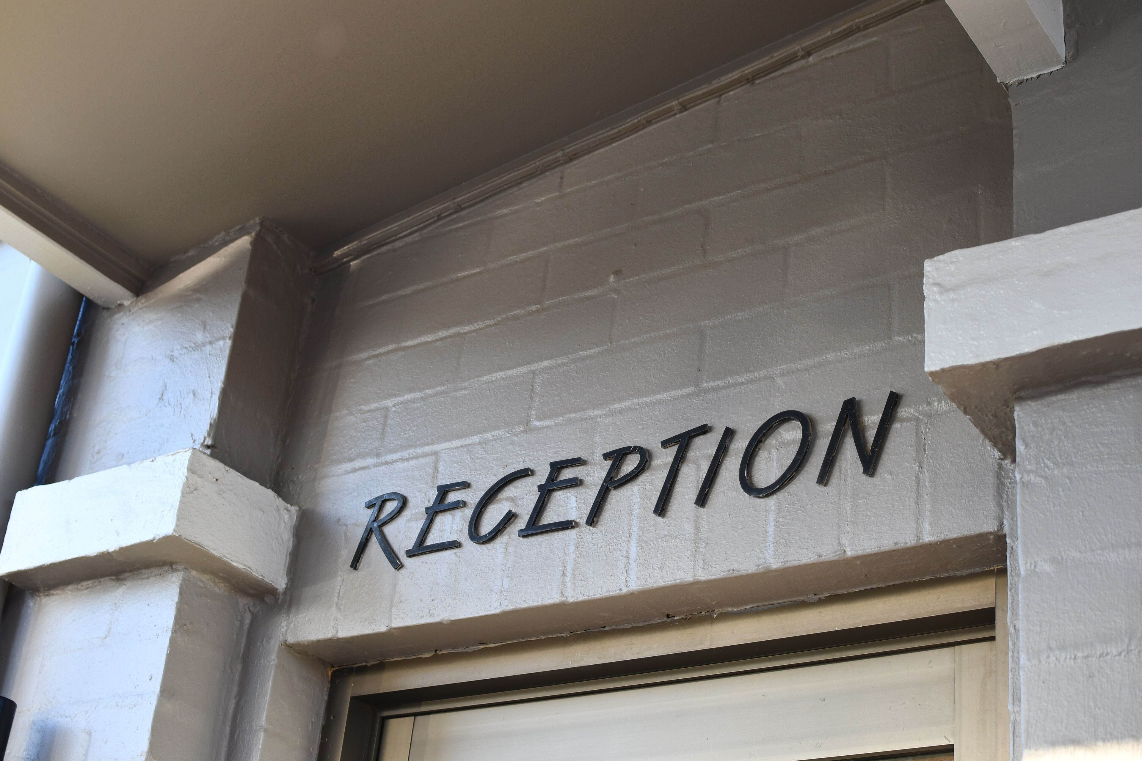 A reception area with a sign that reads "RECEPTION" on a white brick wall.