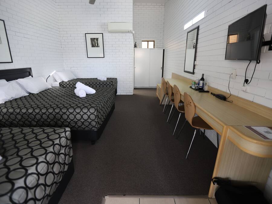 Een hotelkamer met twee bedden, een bureau, stoelen, een televisie en een kledingkast.