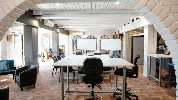 A conference room with a long table, chairs, and a whiteboard.