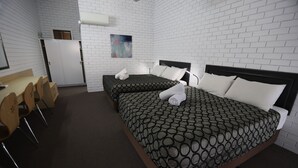 A hotel room with two beds, a desk, and chairs.