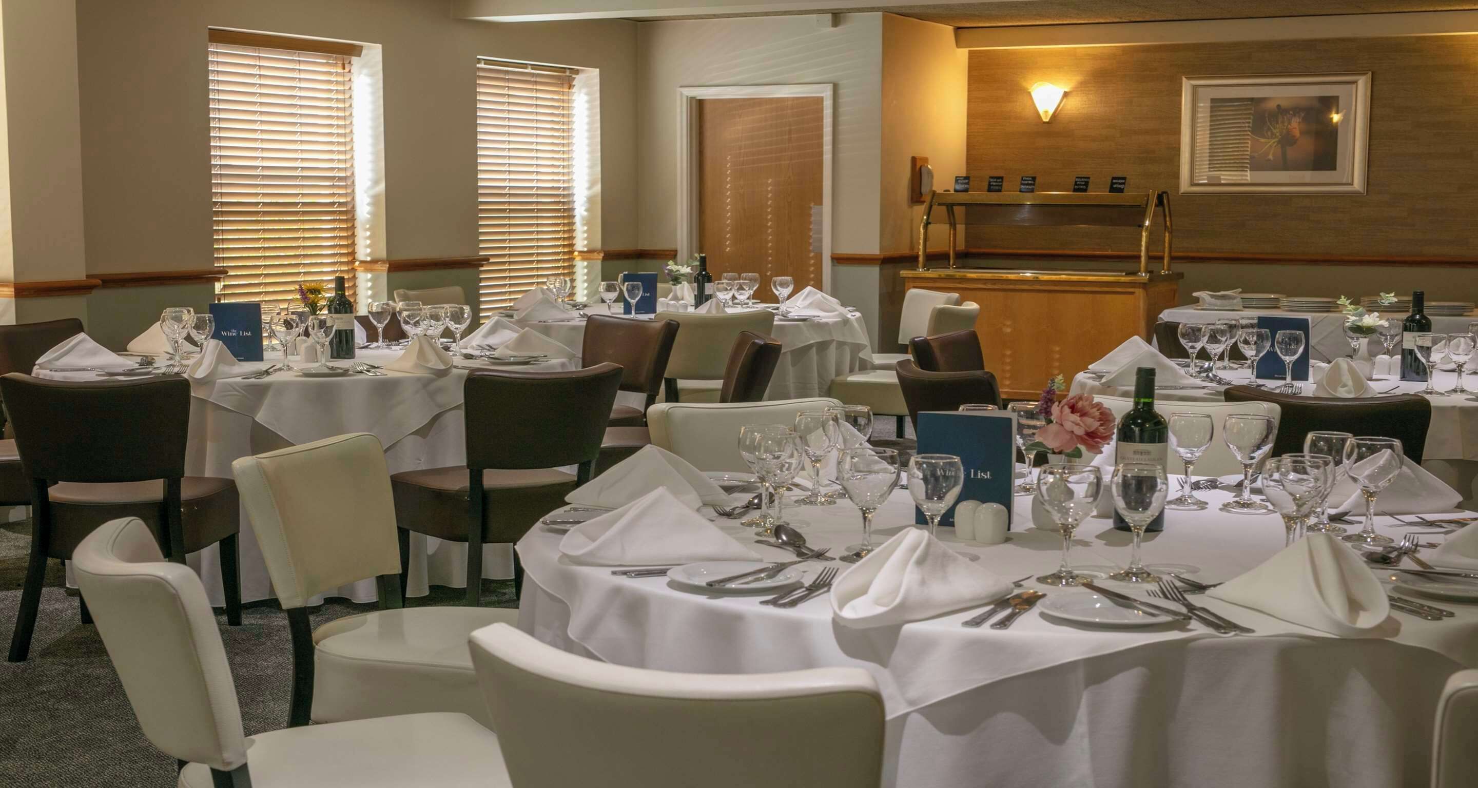 A dining area with multiple tables set for service, a bar area, and a framed picture on the wall.