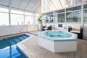 Una piscina interior con un jacuzzi, una planta en maceta y un cartel que dice "SPA RULES".
