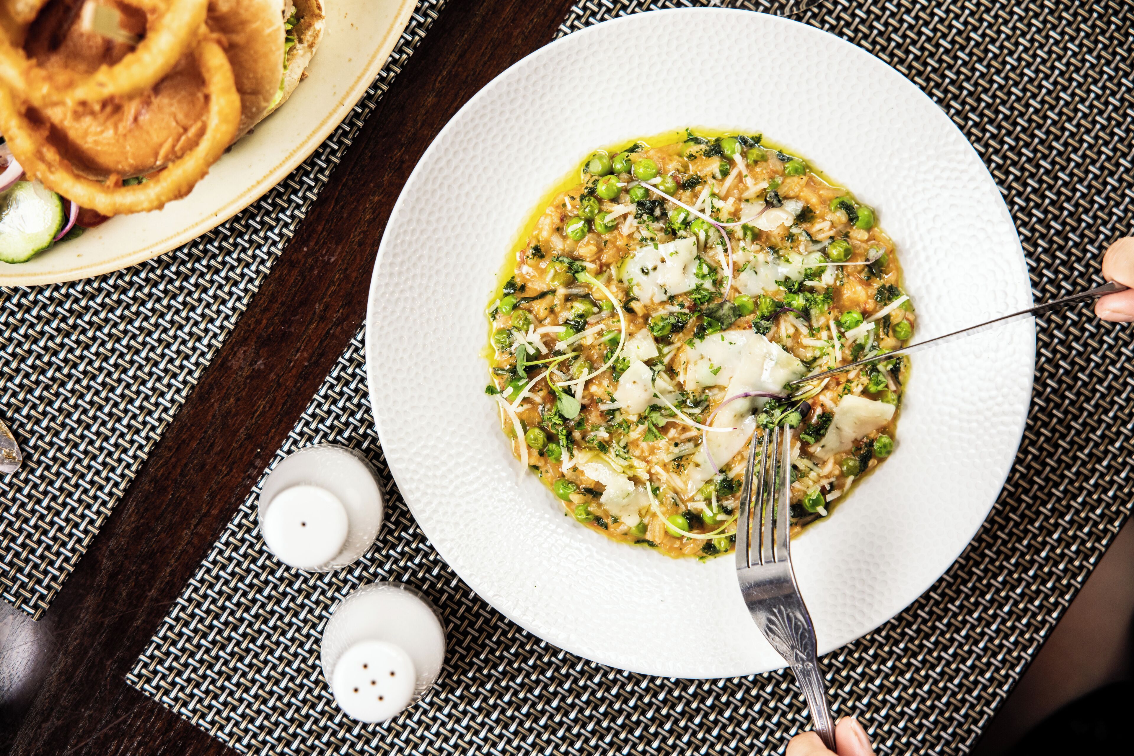 A plate of food with a fork on a textured tablecloth.
