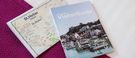 A travel guide book titled 'Visit Jersey Visitor Guide' and a map of St. Helier.