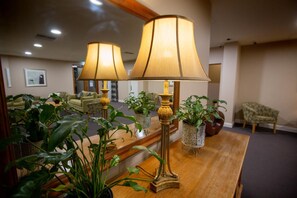 A hotel lobby with two lamps on a wooden table, surrounded by potted plants. - Whyalla Playford Apartments (Whyalla)