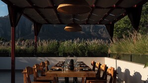 An outdoor dining area with a wooden table and chairs, surrounded by a pergola with hanging lamps. - Hotel Boutique Casa Fernanda - Adults only (Tepoztlán)