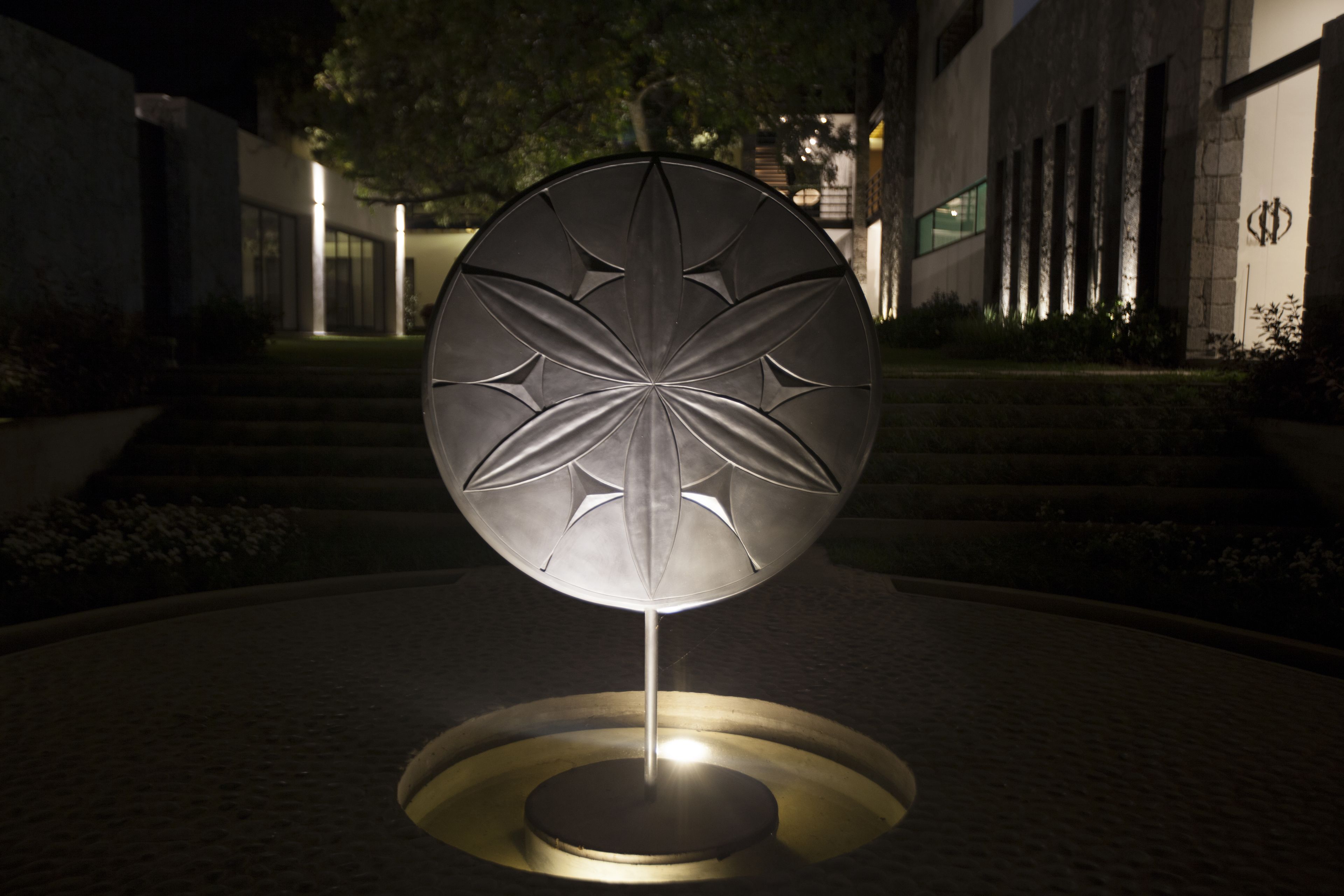 Un edificio moderno con una escultura circular e iluminada en el centro.