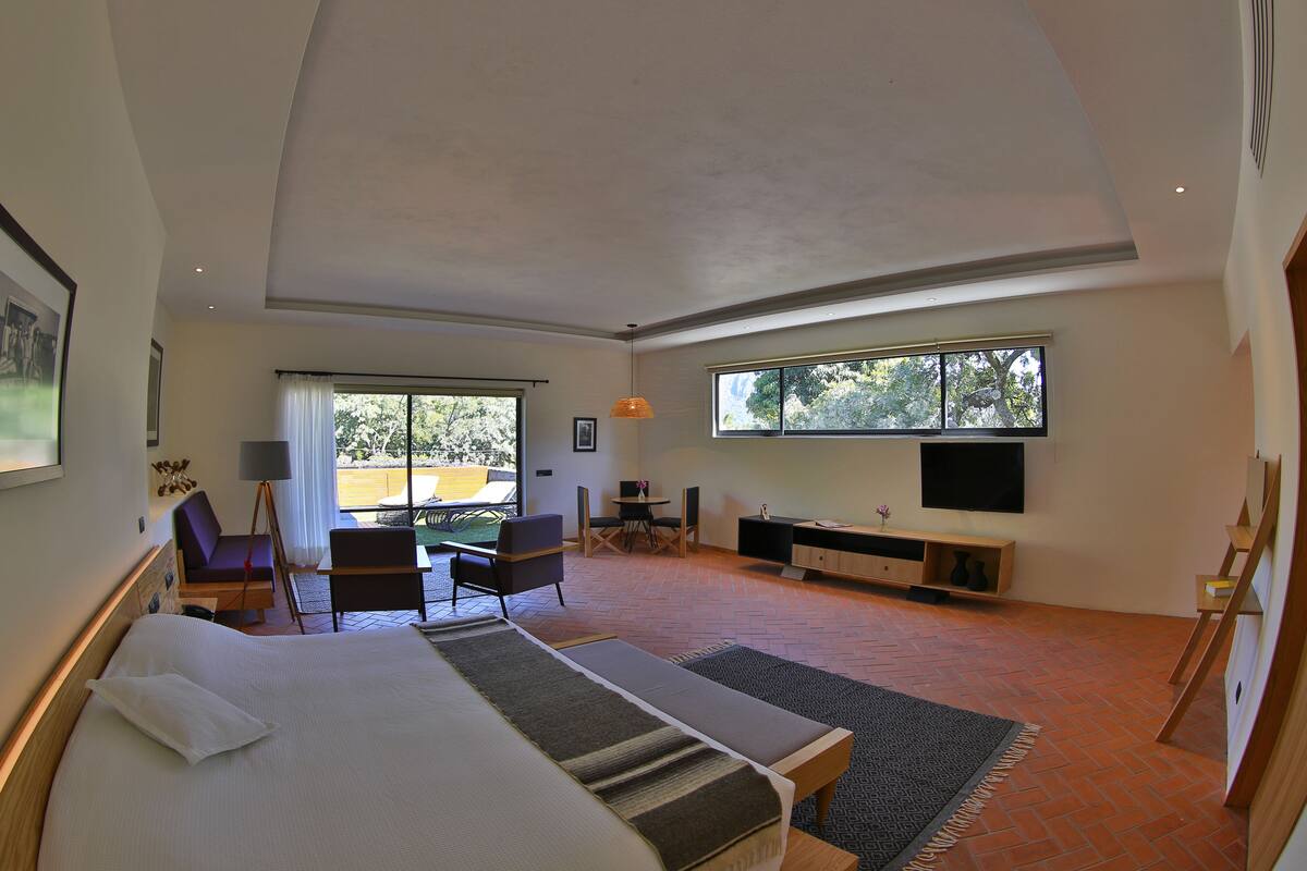 Une chambre d’hôtel moderne dotée d’un grand lit, d’un bureau, d’une chaise, d’une télévision et d’un balcon avec vue.