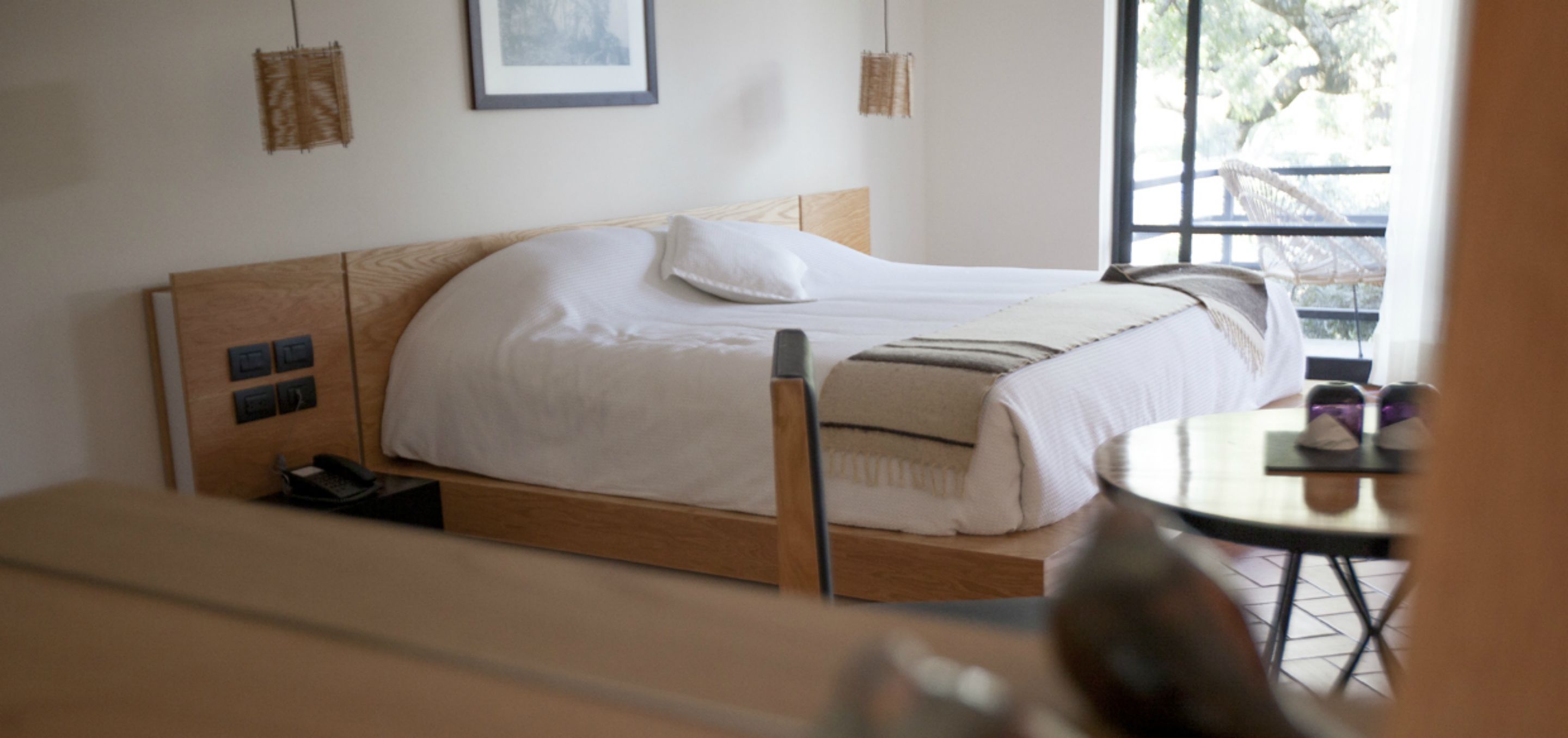 A neatly arranged bedroom with a bed, bedside table, and a small table with a chair.