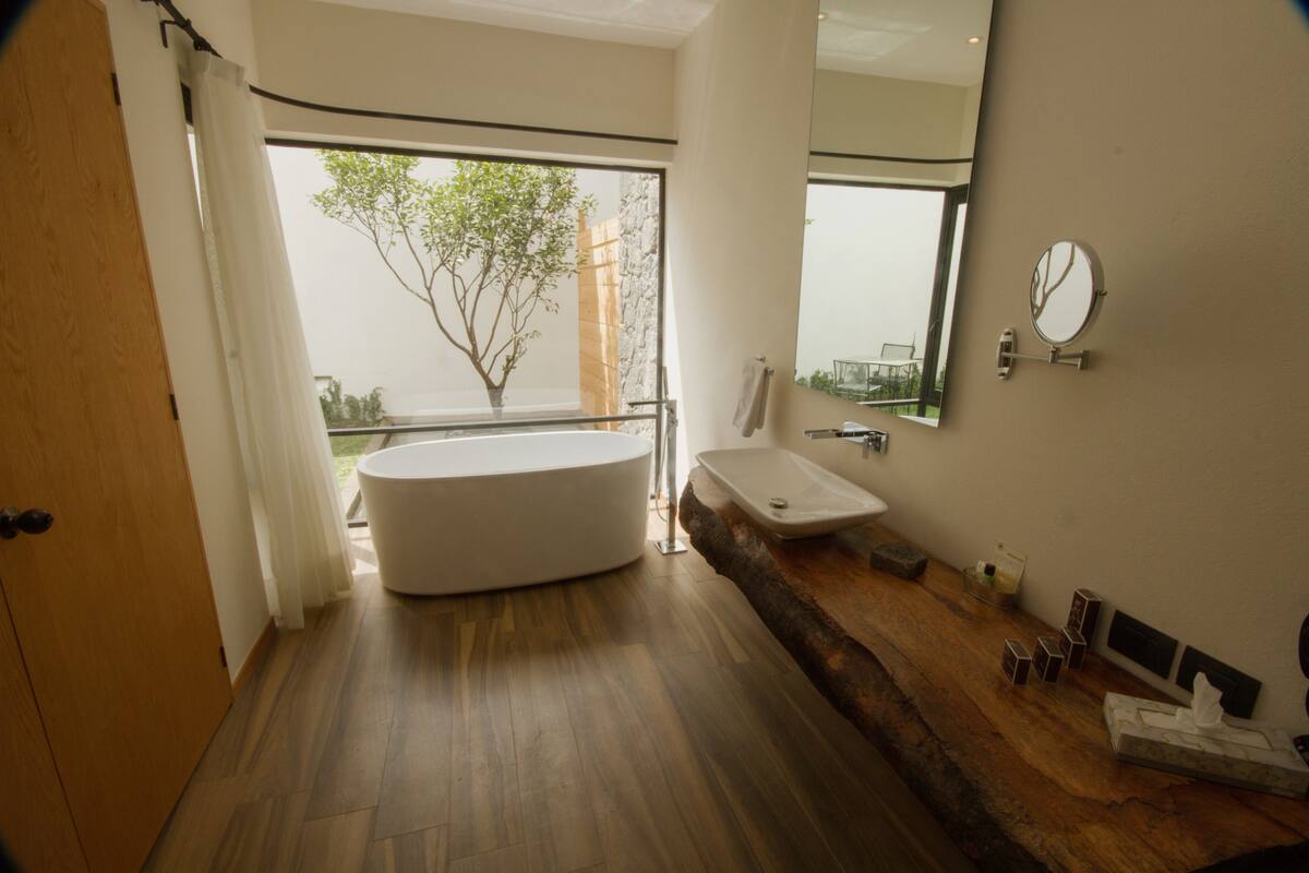 Une salle de bain moderne avec une baignoire sur pieds, un lavabo et un grand miroir.