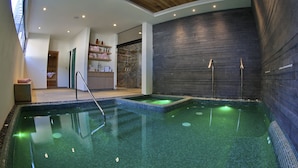 A spa area with a large indoor pool, wooden ceiling, and a stone wall. - Hotel Boutique Casa Fernanda - Adults only (Tepoztlán)