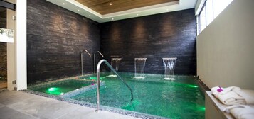 Un área de spa con pared de piedra, una pequeña piscina y una zona de estar con toallas.