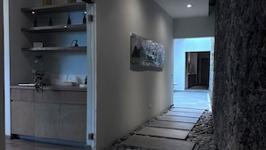 A hallway with a stone pathway, a kitchen area with wooden shelves, and a framed picture on the wall. - Hotel Boutique Casa Fernanda - Adults only (Tepoztlán)