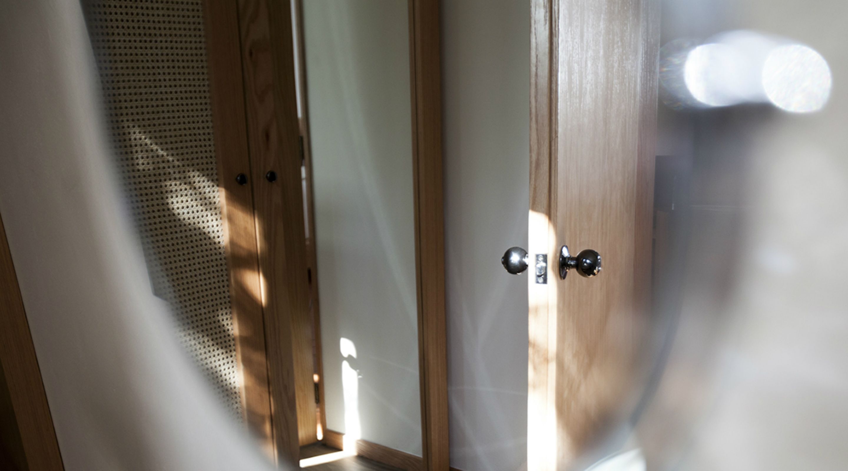 A wooden door with a metal handle and a small window with a metal grill.