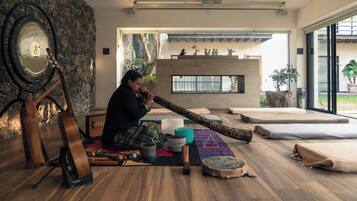 Um quarto com parede de pedra, um espelho grande, uma guitarra, um tambor e uma lareira.