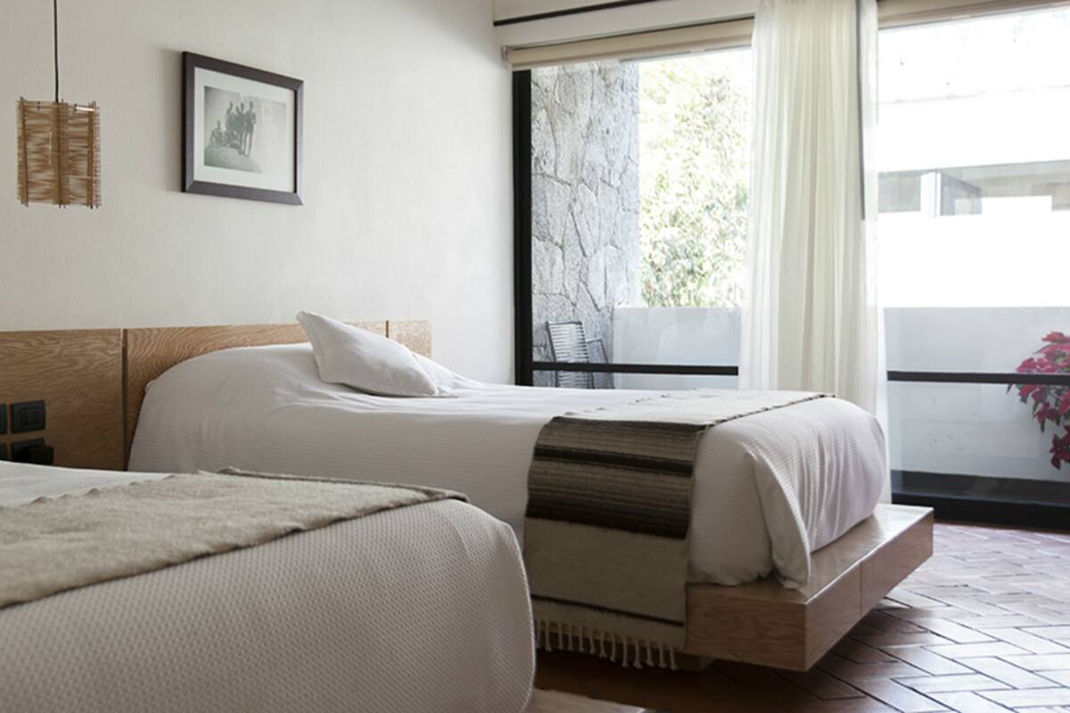 Une chambre d’hôtel avec deux lits, une fenêtre donnant sur un beau paysage et un tableau accroché au mur.