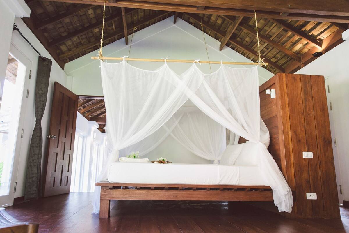 Un letto a baldacchino, pavimento in legno e soffitto alto.