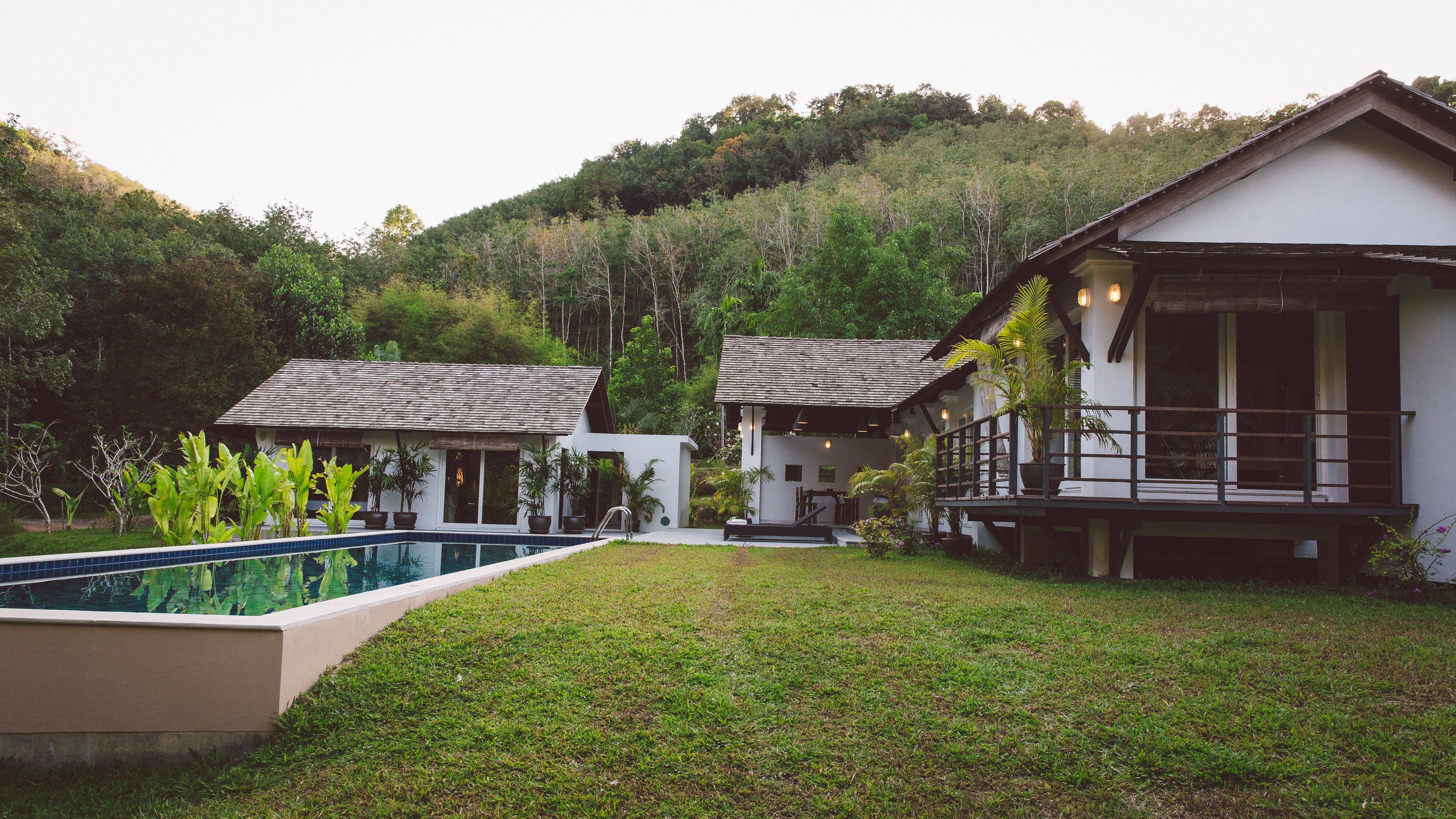 A modern resort with a swimming pool, lush greenery, and multiple buildings with distinct architectural styles.