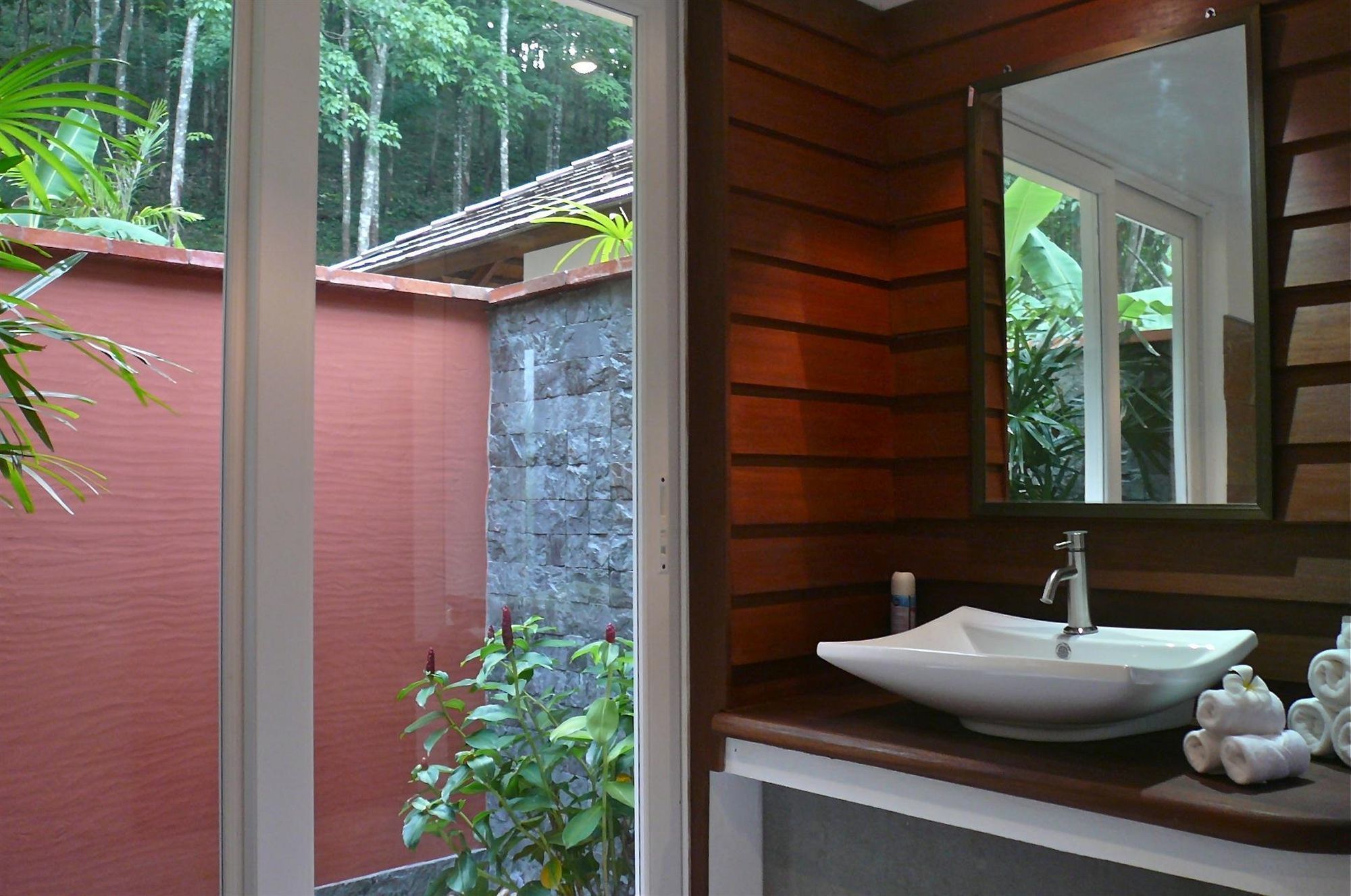 A bathroom with a large window, a white sink, and a mirror.