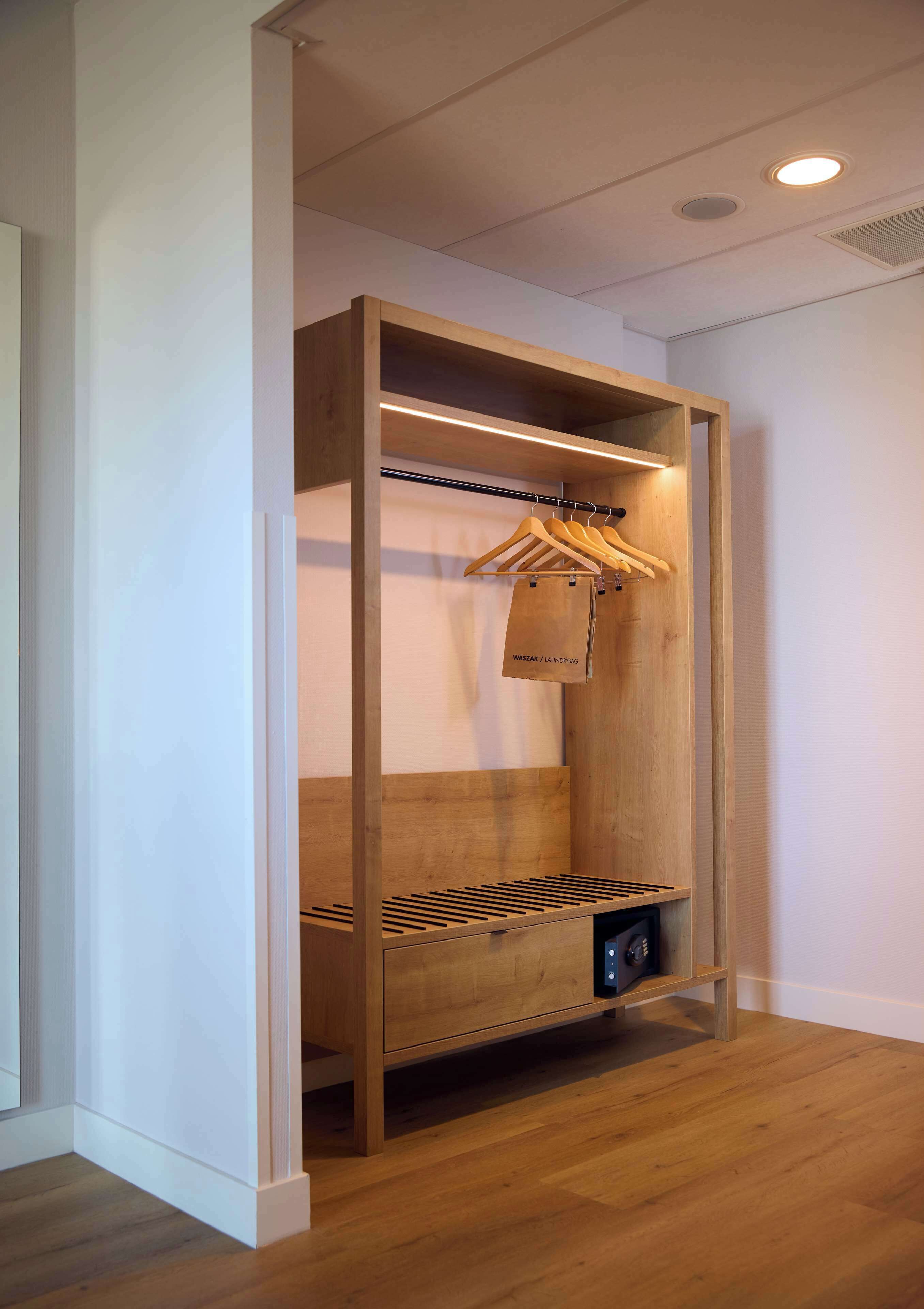 Un armario de madera con barra para colgar y calentador incorporado.