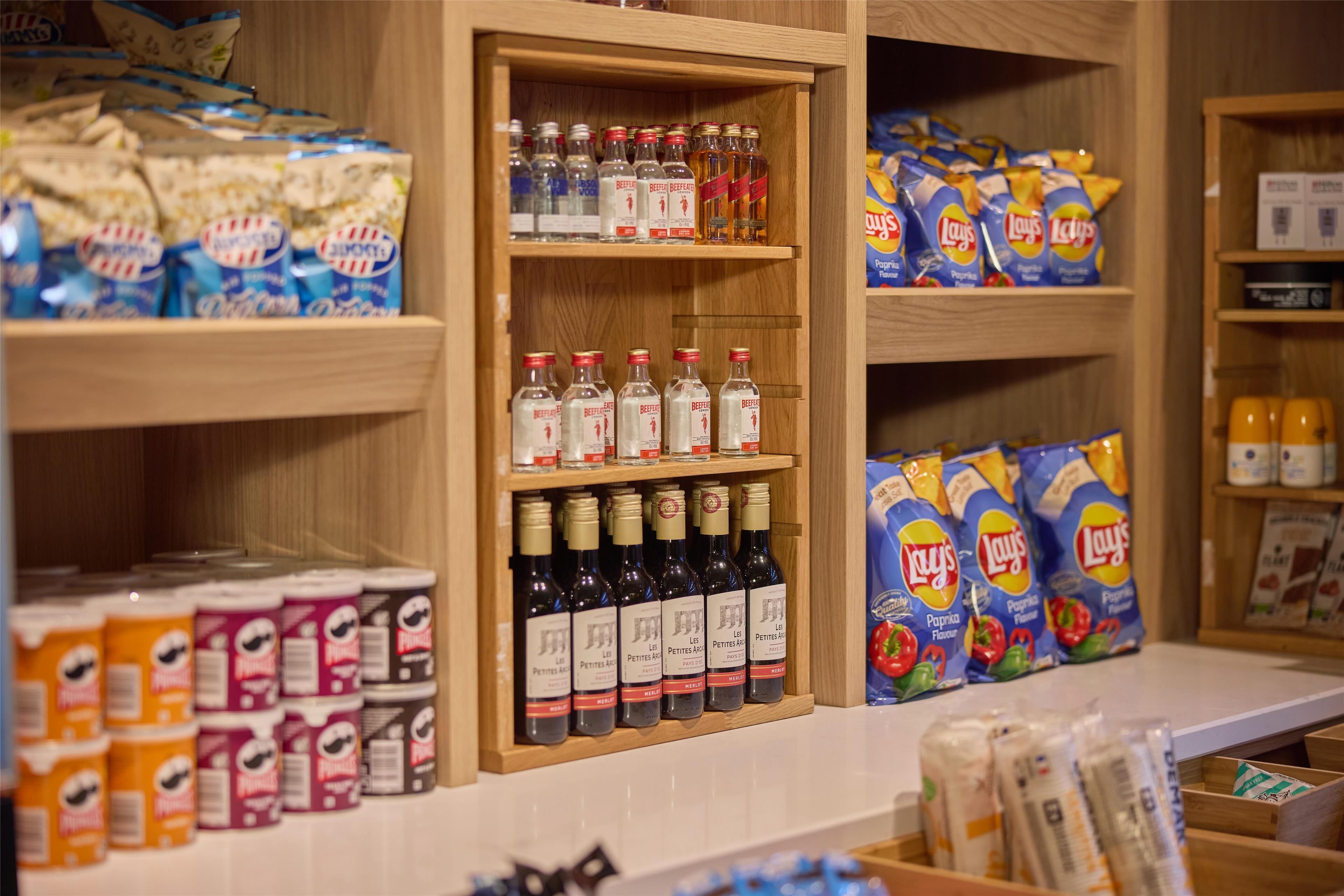 A shelf stocked with various snacks and beverages, including Lay's chips, Lay's potato chips, and bottles of Lay's beer.