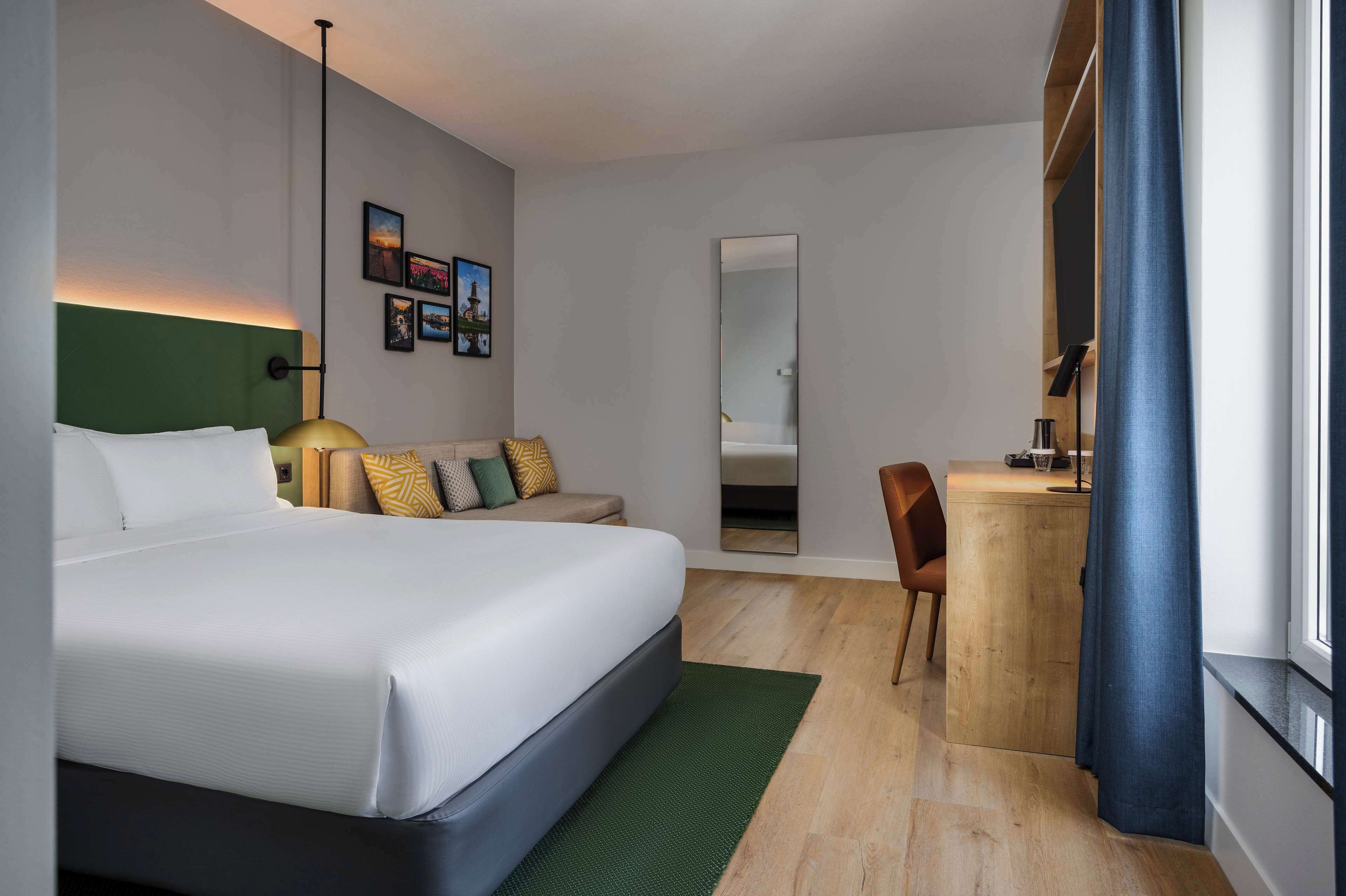 Una habitación de hotel moderna con una cama grande, un escritorio y un espejo.